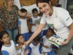 Maria Claudia Kohler, coordenadora de Educação Ambiental do Projeto, entregando as cartilhas de educação ambiental marinha do Projeto