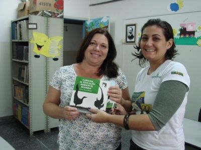 Cynthia Ranieri, assistente de Educação Ambiental do Projeto, entregando cartilha à escola Padre Leonardo Nunes