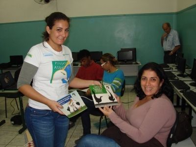 Cynthia Ranieri, do Projeto Albatroz, entrega cartilhas à professora da escola municipal Martins Fontes